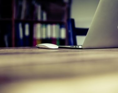 laptop and computer mouse on table in library